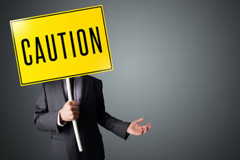 Businessman standing and holding a yellow caution sign in front of his head.jpeg
